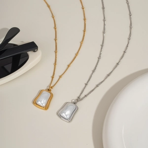 Gros plan détaillé des colliers avec pendentifs perles dorés et argentés sur fond beige