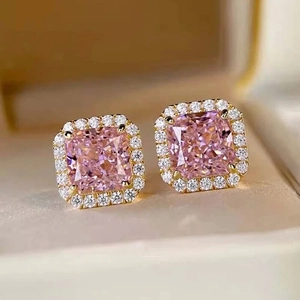 Close-up of pink square gemstone stud earrings with gold halo setting in a jewelry box