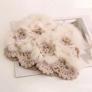 Detail of beige hand-crocheted knit hat featuring fur-trimmed floral patterns