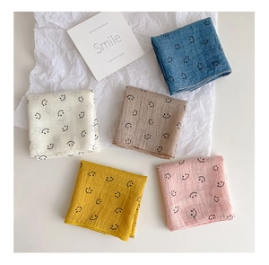 Flat lay of colorful muslin cotton bibs with minimalist smile prints on white paper