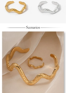 Detailed view of textured wavy gold and silver open ring set on silk fabric
