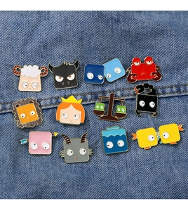 Detailed set of 12 cartoon zodiac enamel pins displayed on blue denim fabric background
