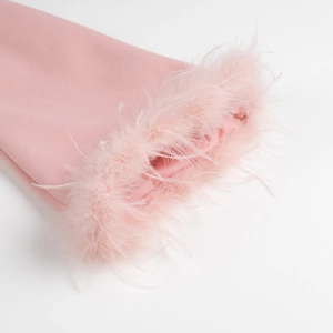 Gros plan détaillé de la manche du manteau en laine rose avec bordure en plumes douces