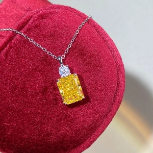 Macro shot of rectangular yellow gemstone pendant on silver chain with red velvet backdrop