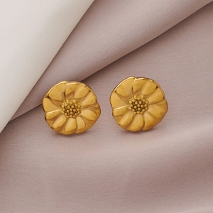 Detailed close-up of golden sunflower earrings with hammered texture on silk fabric