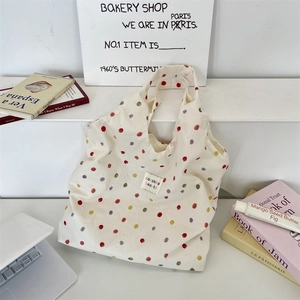 Detailed view of canvas tote bag with colorful polka dots and woven rectangular label