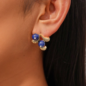Macro shot of gold-plated hammered metal earrings with blue lapis and diamond details