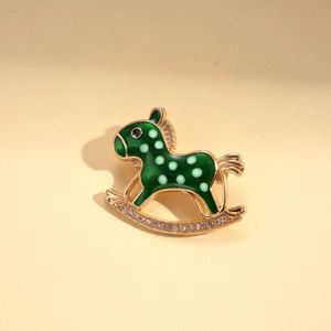 Detailed close-up of a green rocking horse brooch with gold base and sparkling crystals