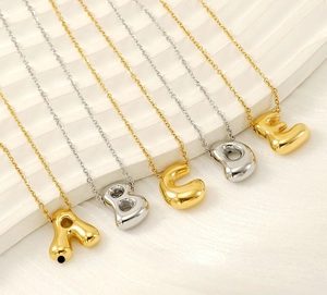 Detail of 3D puffy A-E letter pendants in gold and silver polished stainless steel