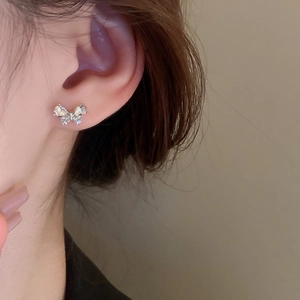 Detail of a sparkling butterfly stud earring with clear zircons on a silver metal base