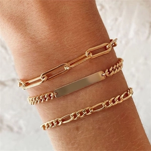 Close-up of three layered gold chains featuring a paperclip, Cuban ID, and Figaro link