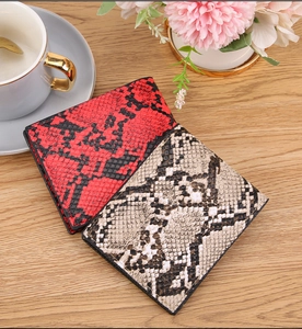 Close-up of red and grey faux snakeskin leather wallets on a wooden surface