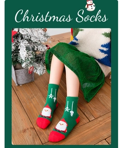 Detail view of dark green Christmas socks featuring Santa Claus patterns and red accents