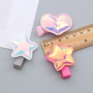 Iridescent heart and star hair clips for girls showing size on a measuring ruler