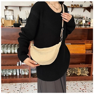 Detailed view of beige corduroy crescent crossbody bag with adjustable strap on model