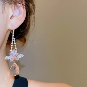Detail showing a gold earring with pink zircon flower and water drop shaped pendant