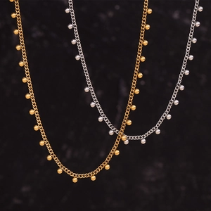 Detail view of 18K gold and silver beaded necklaces with dense link chains on dark background