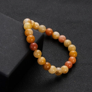 Detailed close-up of warm-toned gemstone beaded bracelet featuring natural texture on black box