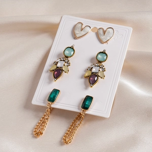 Vue détaillée des puces cœur, boucles d'oreilles gemmes colorées et pompons émeraude
