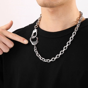 Détail d'un collier chaîne NK en acier inoxydable argenté avec pendentifs menottes
