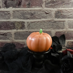 Decorazione a candela a zucca arancione brillante con gambo verde su pizzo nero gotico