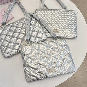 Detailed view of silver quilted laptop sleeves with heart and bow patterns on a table