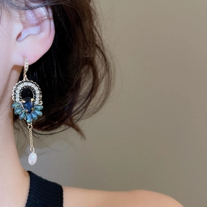 Détail de boucles d'oreilles vintage en or avec cristaux bleus et franges de perles