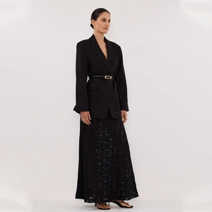 Detail of a chic black lace maxi skirt paired with a slim belt and a tailored blazer