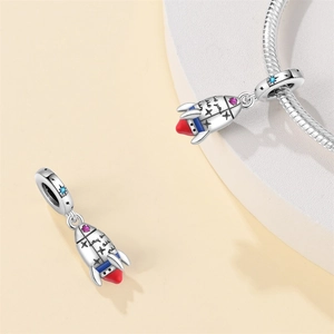 Detail of silver rocket charm with colorful enamel and inlaid gemstones on a snake chain