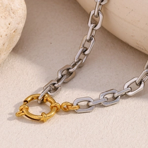 Detail of square silver chain link with a golden round spring clasp on stone