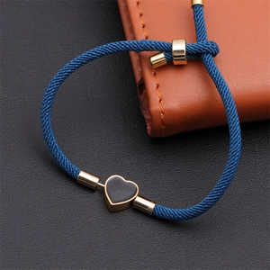 Detailed view of adjustable dark blue woven bracelet with a gold heart pendant charm