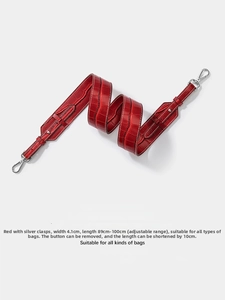 Detail of red crocodile pattern bag strap with silver metal buckles and adjustable length