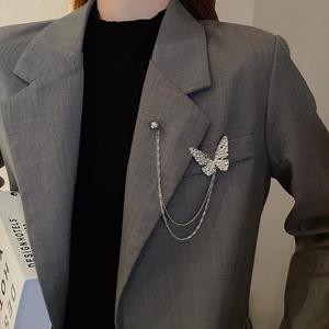Detail of silver butterfly brooch with tassel chain and gray pearl on a blazer