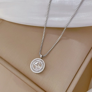 Détail macro d'un collier en acier titane avec un pendentif rond auréolé de diamants