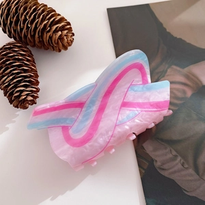 Close-up of pink acrylic hair claw clip with blue and deep pink wavy pattern and glossy finish