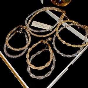 Close-up of gold and silver twisted mesh bracelets with sparkling crystals on black background
