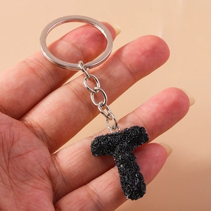 Close-up of letter T keychain with black rose texture and silver metal ring
