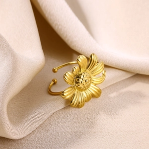 Détail d'une bague tournesol plaquée or sur un fond de tissu en velours champagne