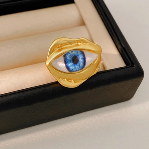 Close-up of irregular gold ring featuring a realistic blue eye design with matte texture