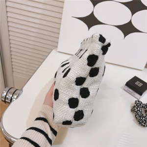 Détail d'un sac à main tricoté blanc à pois noirs montrant la texture épaisse du tissage