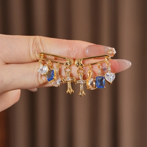 Detailed shot of gold pin earrings featuring blue and white zircon cross and heart charms