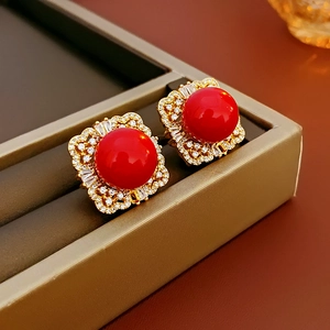 Detail view of vintage pearl earrings with red center stone and gold square frame