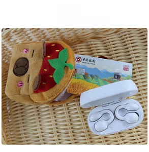 Detail of Capybara strawberry plush pouch with open-ear wireless bluetooth earbuds