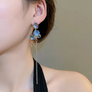 Elegant silver tassel earrings with blue resin beads on a fashion model side profile