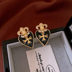 Detail view of heart-shaped black enamel earrings with cross and iris design in jewelry box