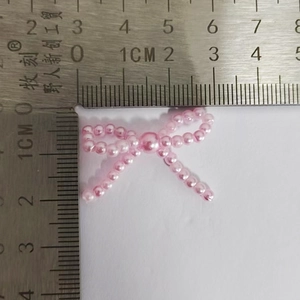 Pink pearl bow accessory measuring approximately 3.5cm wide shown with a steel ruler
