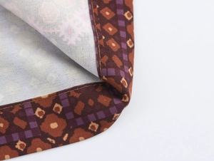 Detail of woven fabric with brown and purple geometric patterns and fine stitching