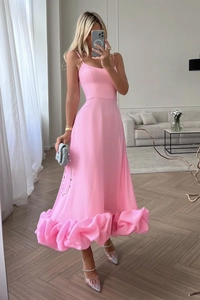 Detailed view of pink spaghetti strap maxi dress featuring dramatic ruffled tiered hem