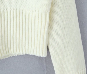Macro shot of white knitted top showing detailed ribbed hem and dense weave texture