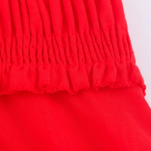 Close-up of red smocking fabric details with delicate ruffled edges on the midi dress